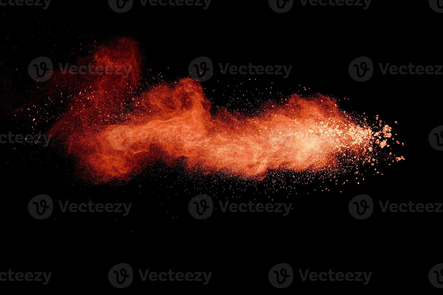 Abstract orange powder explosion on black background. Freeze motion of orange powder splash. photo