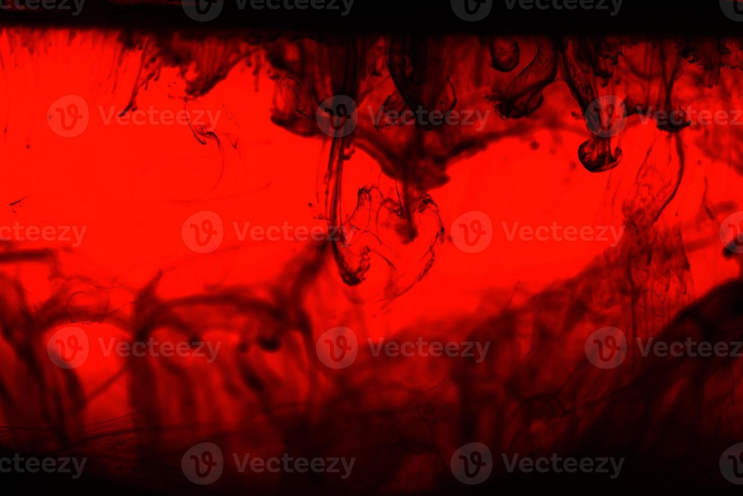Abstract black alcrylic ink in water on red background.Fantasy chaotic colorful fractal pattern. photo
