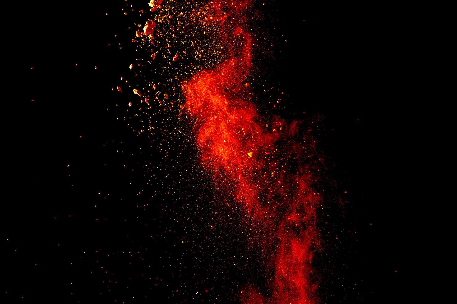 Red orange color powder explosion cloud isolated on black background. photo