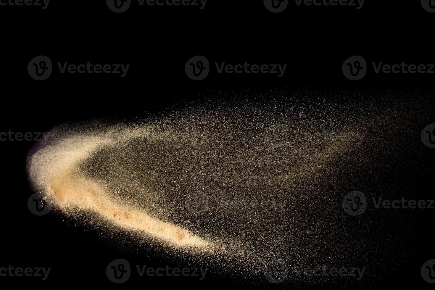 Abstract sand cloud.Golden colored sand splash agianst dark background.Yellow sand fly wave in the air. Sand explode on black background ,throwing freeze stop motion concept. photo