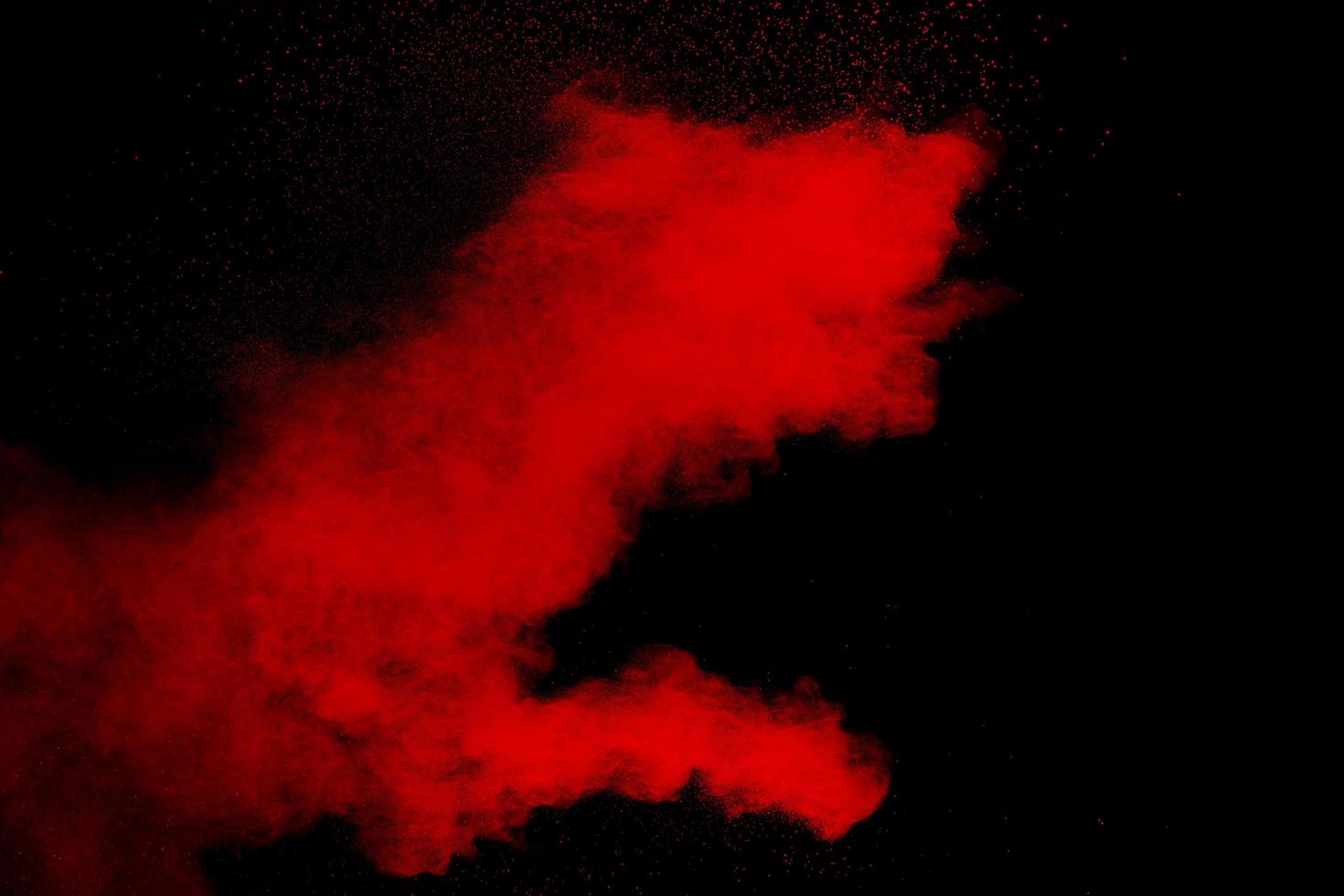 Red color powder explosion on black background.Freeze motion of red dust particles splashing. photo
