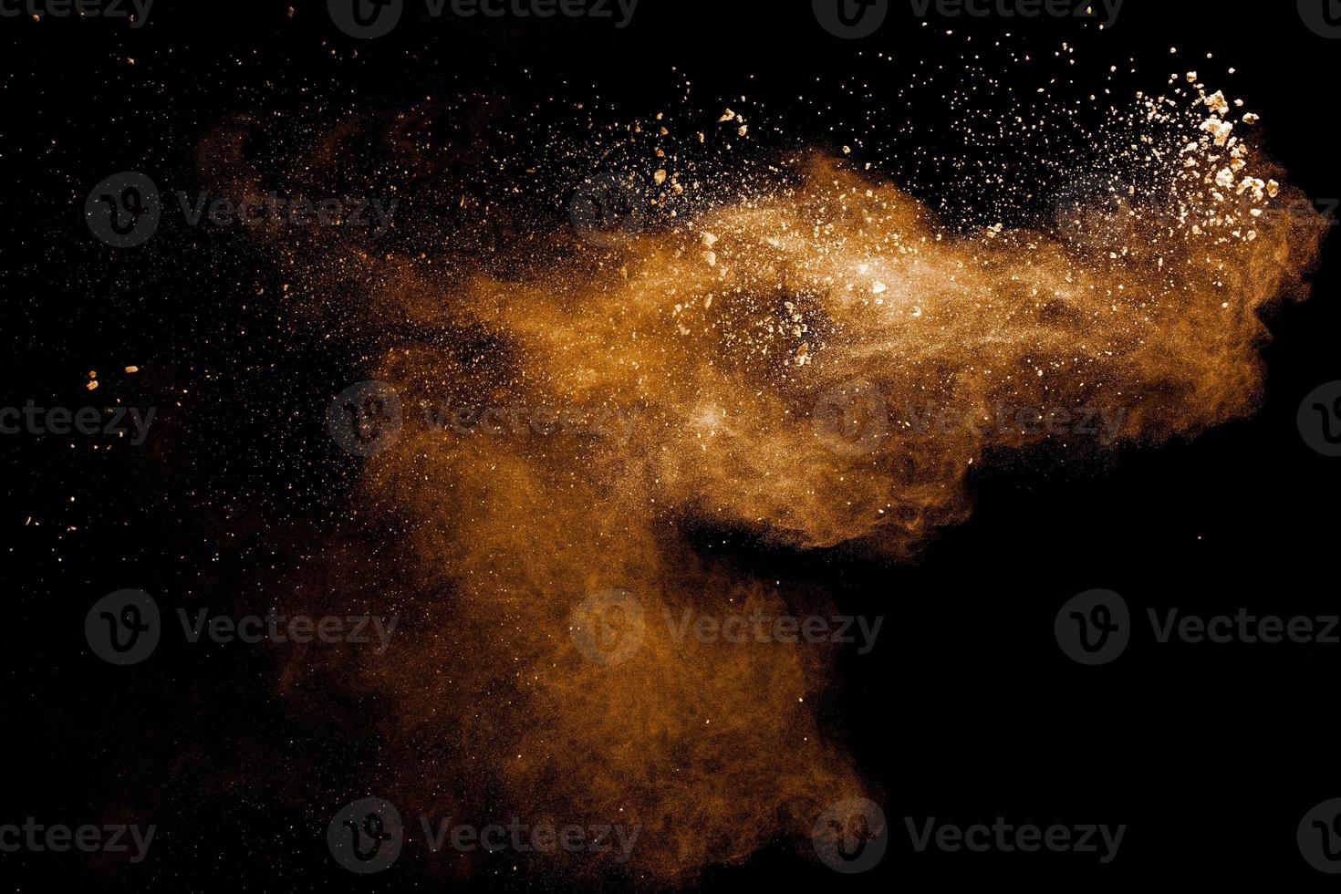 Abstract brown dust explosion on black background.Brown powder splashing. photo
