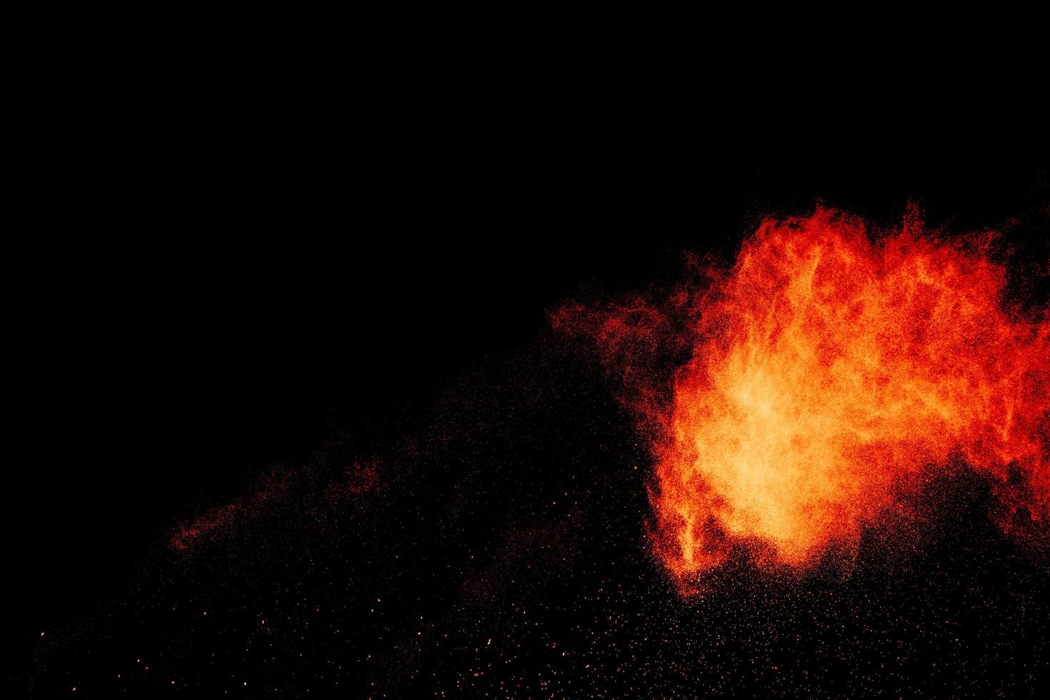 Red orange color powder explosion cloud isolated on black background. photo