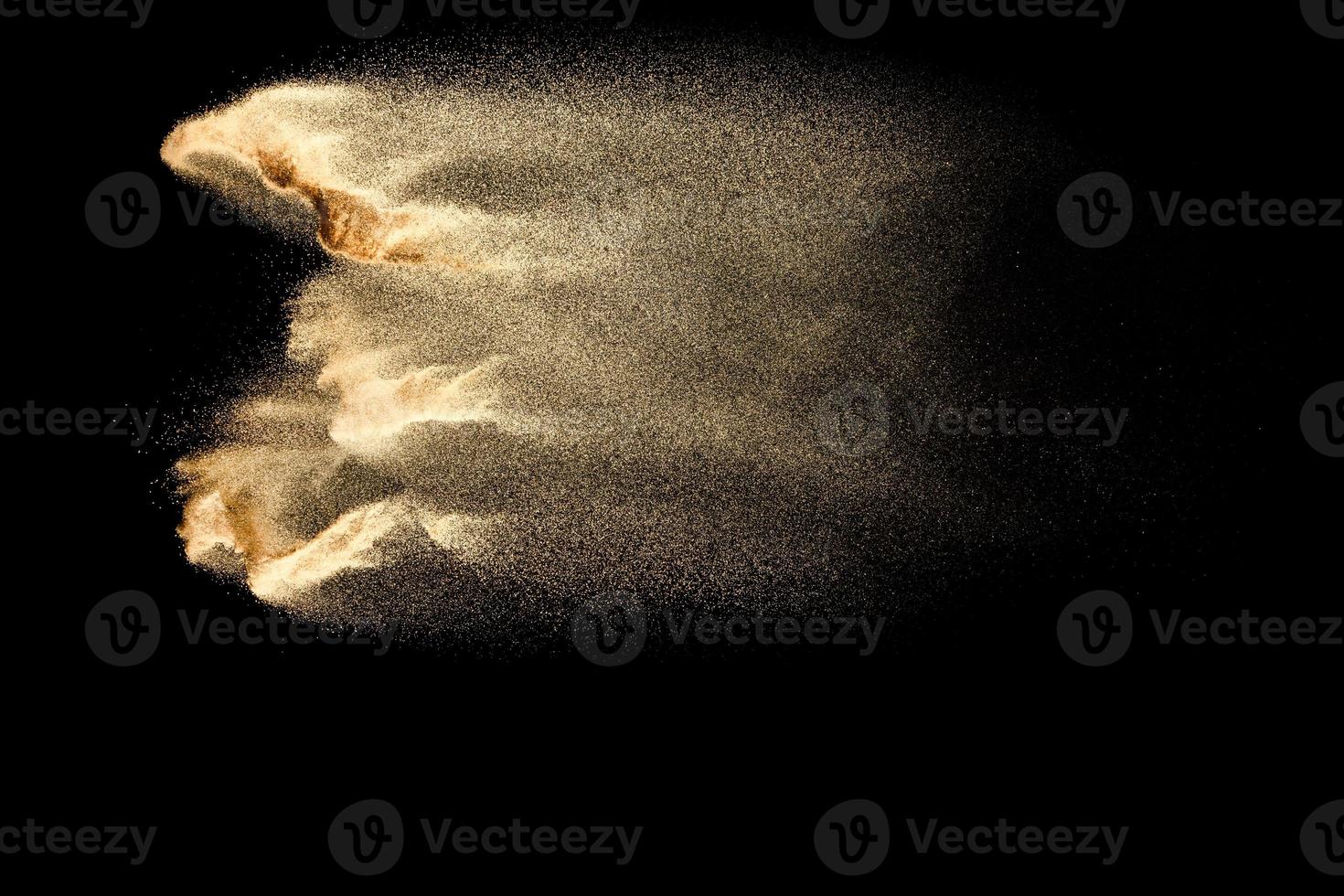 Abstract sand cloud.Golden colored sand splash agianst dark background.Yellow sand fly wave in the air. Sand explode on black background ,throwing freeze stop motion concept. photo