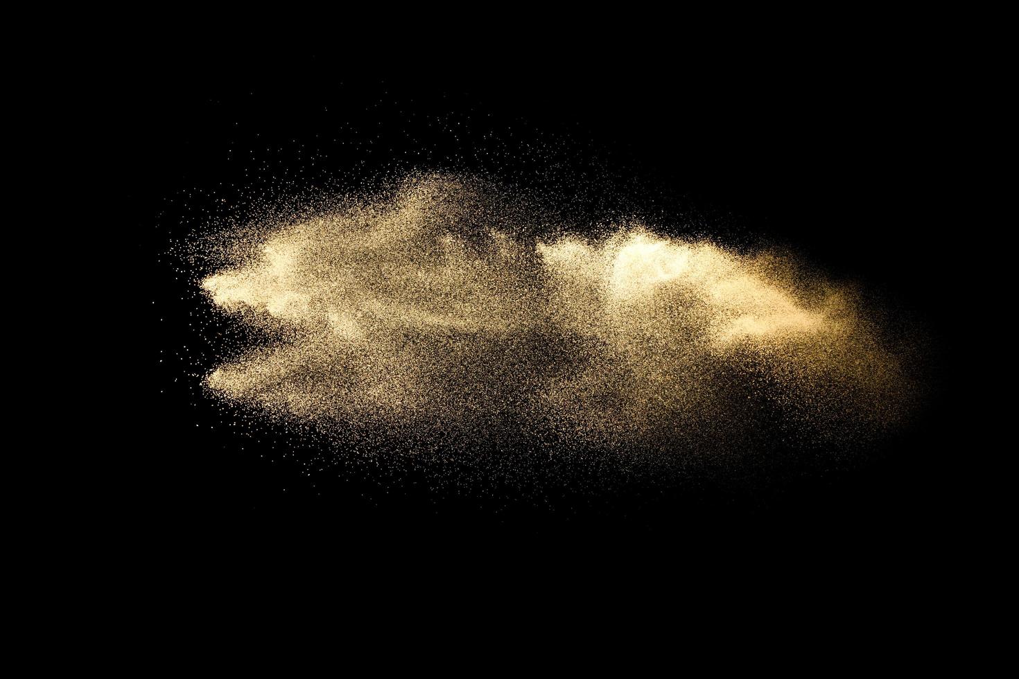 Abstract sand cloud.Golden colored sand splash agianst dark background.Yellow sand fly wave in the air. Sand explode on black background ,throwing freeze stop motion concept. photo