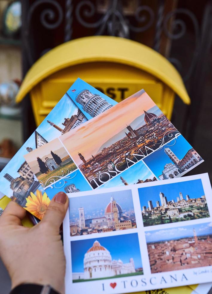 PISA, ITALY - OCTOBER 15, 2021 Hand holding postcards by the post box photo
