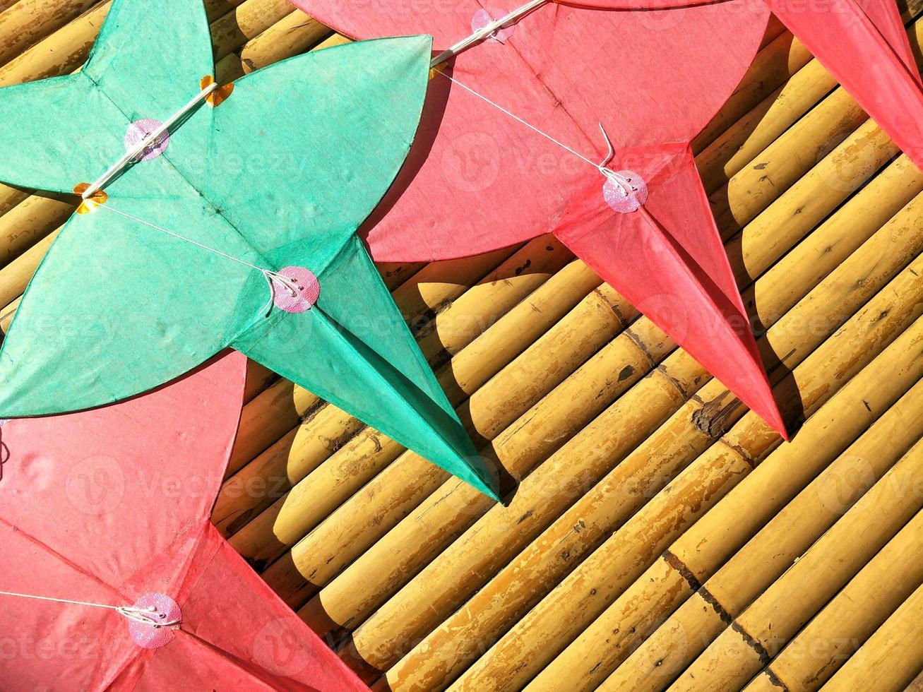 Flat lay of red and green star-shaped kites on bamboo litter, Thai art of craft concept photo
