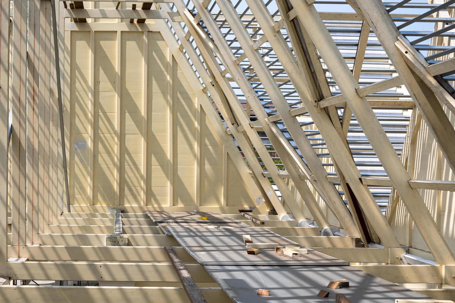 Sunlight and shadow on surface of white wooden roof truss structure with material under construction, renovation and architecture concept photo