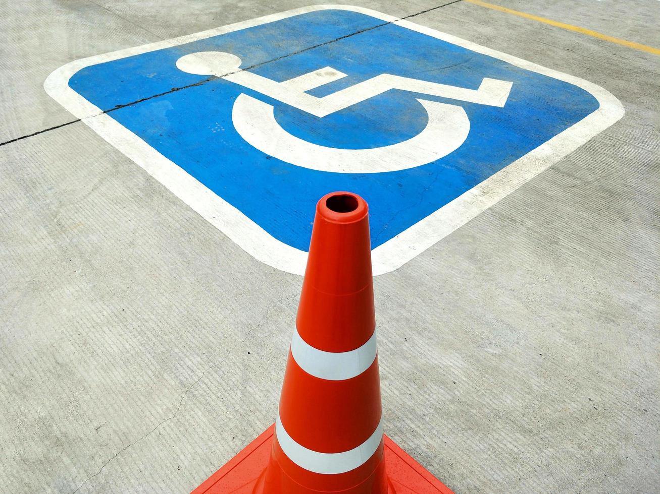 Red traffic cone and sign of wheelchair on the ground in hospital parking photo