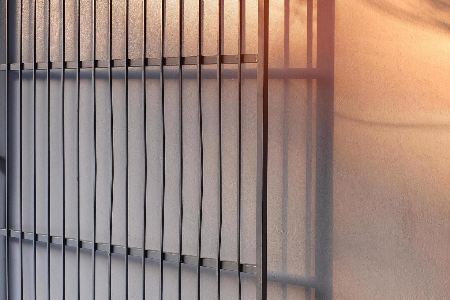 Sunlight and shadow on surface of the old iron fence gate opening with cement wall background, side view with copy space photo