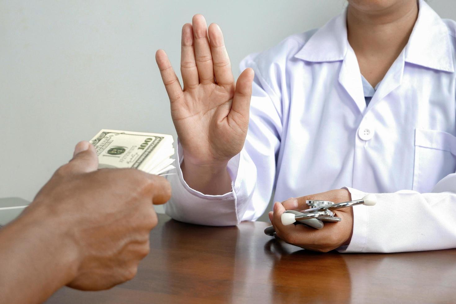 Cropped image of female doctor's hand refusing to take bribe from patient man at doctor office, corruption and bribe in medical concept photo