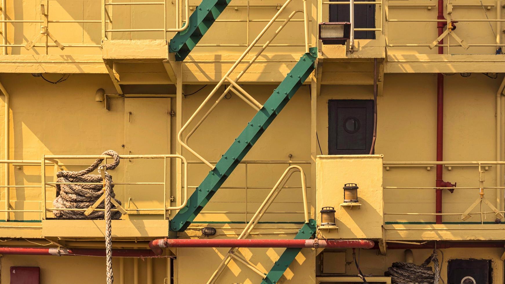 Part of green stairs up and down with railing on aft side of the old big yellow metal ship photo