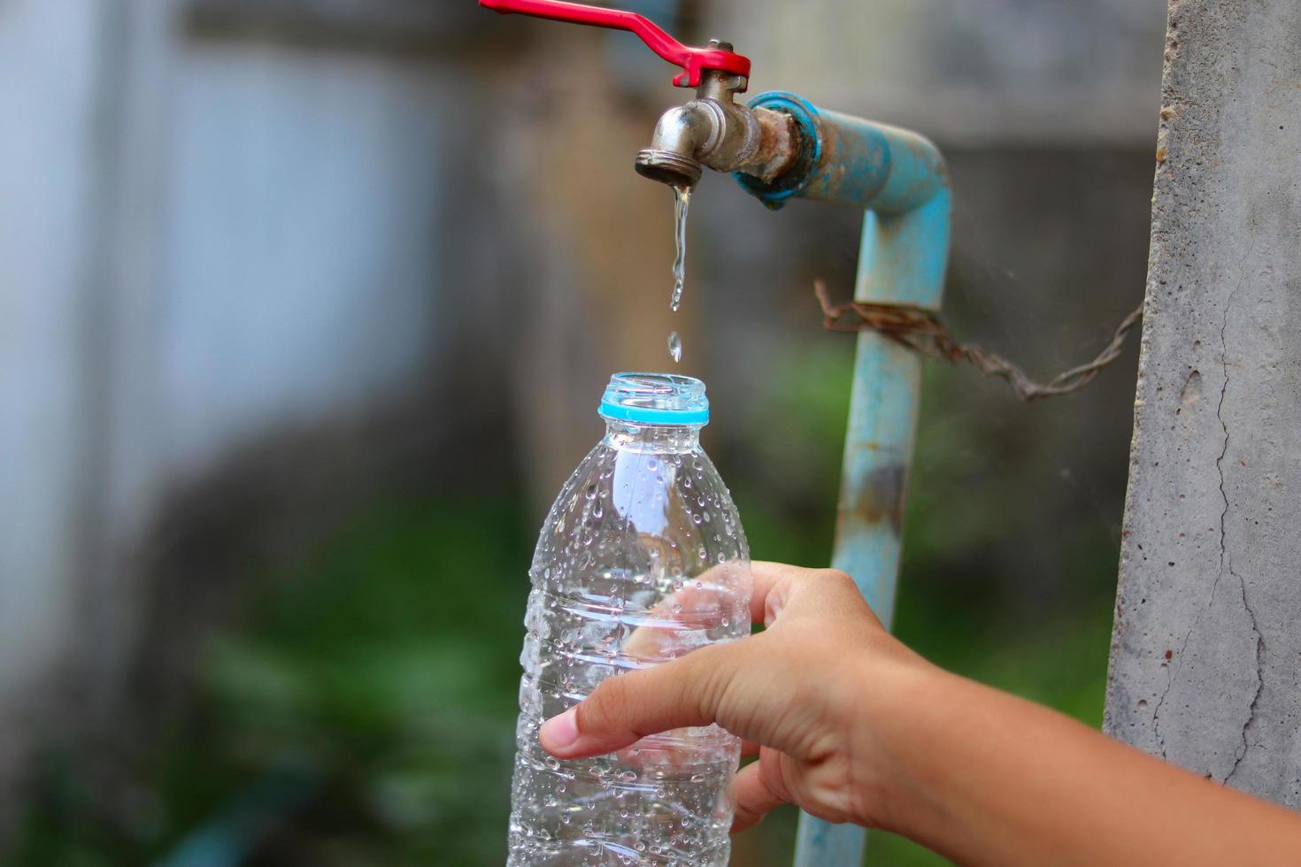 mano joven recogiendo agua de un viejo grifo de agua foto