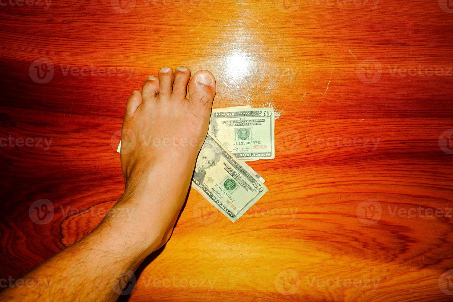 Men foot treads on money banknote. Dollars money. photo