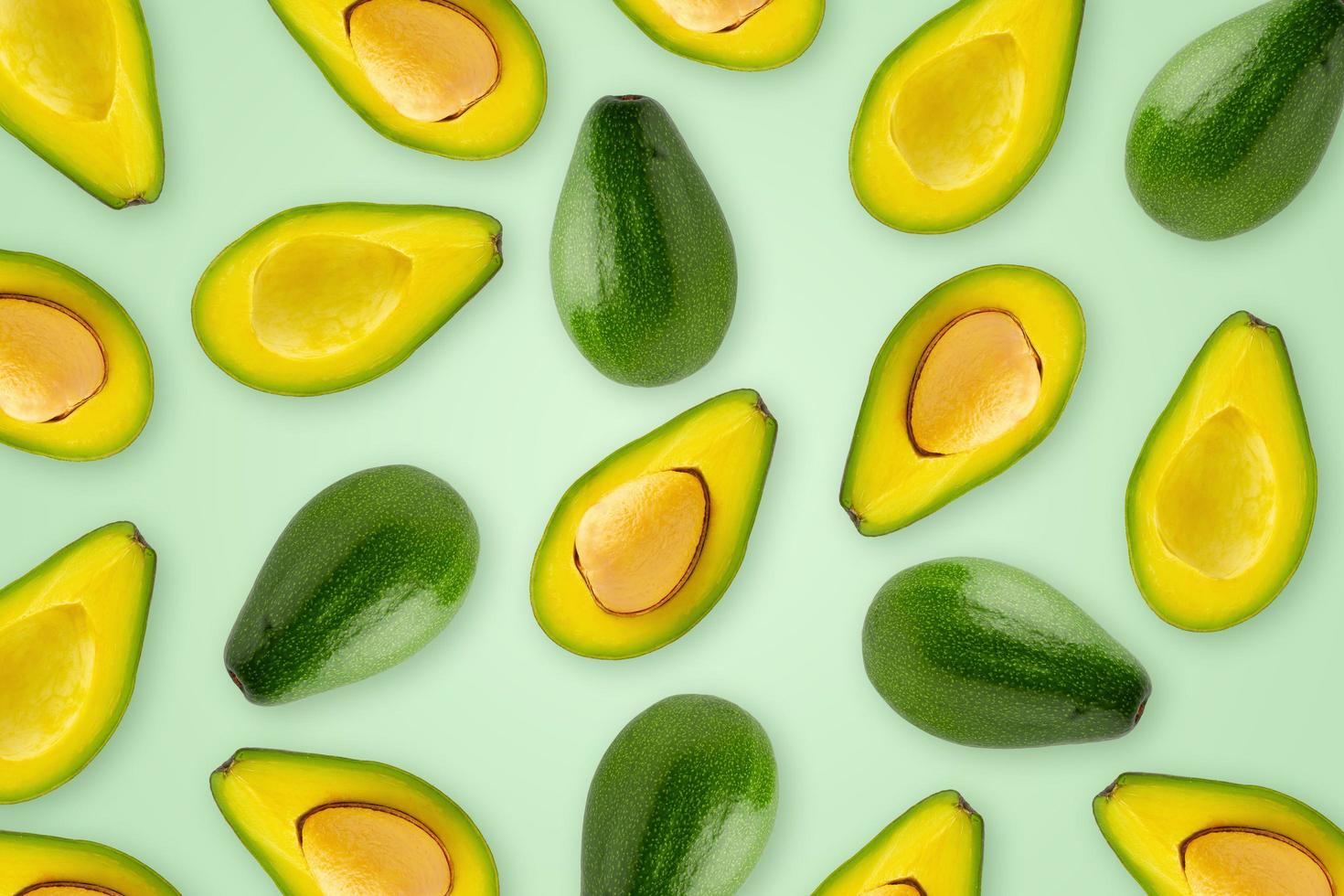 Slices and half of avocado on a green wallpeaper background. photo