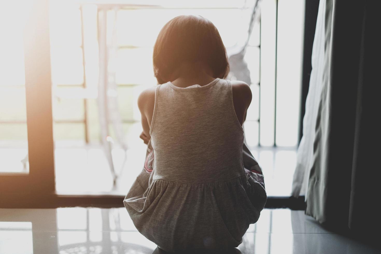 una niña triste estaba llorando y sentada en el suelo cerca de la puerta de la habitación. ella fue intimidada, infeliz, molesta, se siente enferma. concepto solitario. foto