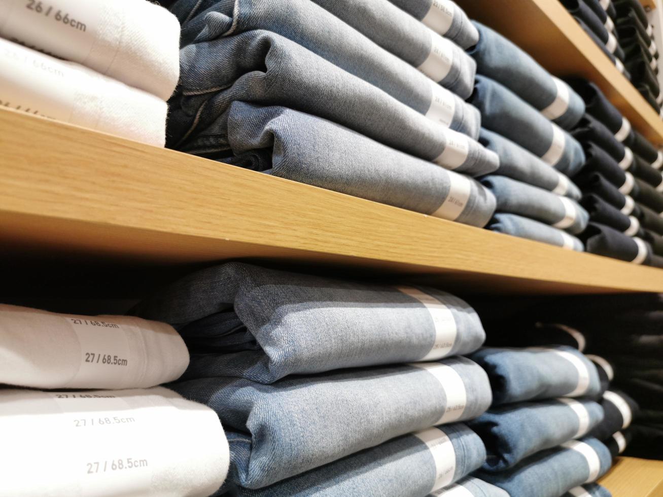 filas de pantalones de mezclilla en los estantes de la tienda de cena o de la tienda minorista. pila de pantalones vaqueros. foto