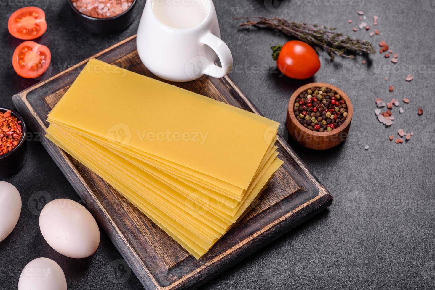 Stack of lasagna sheets on a dark concrete background. Ingredients for lasagna photo