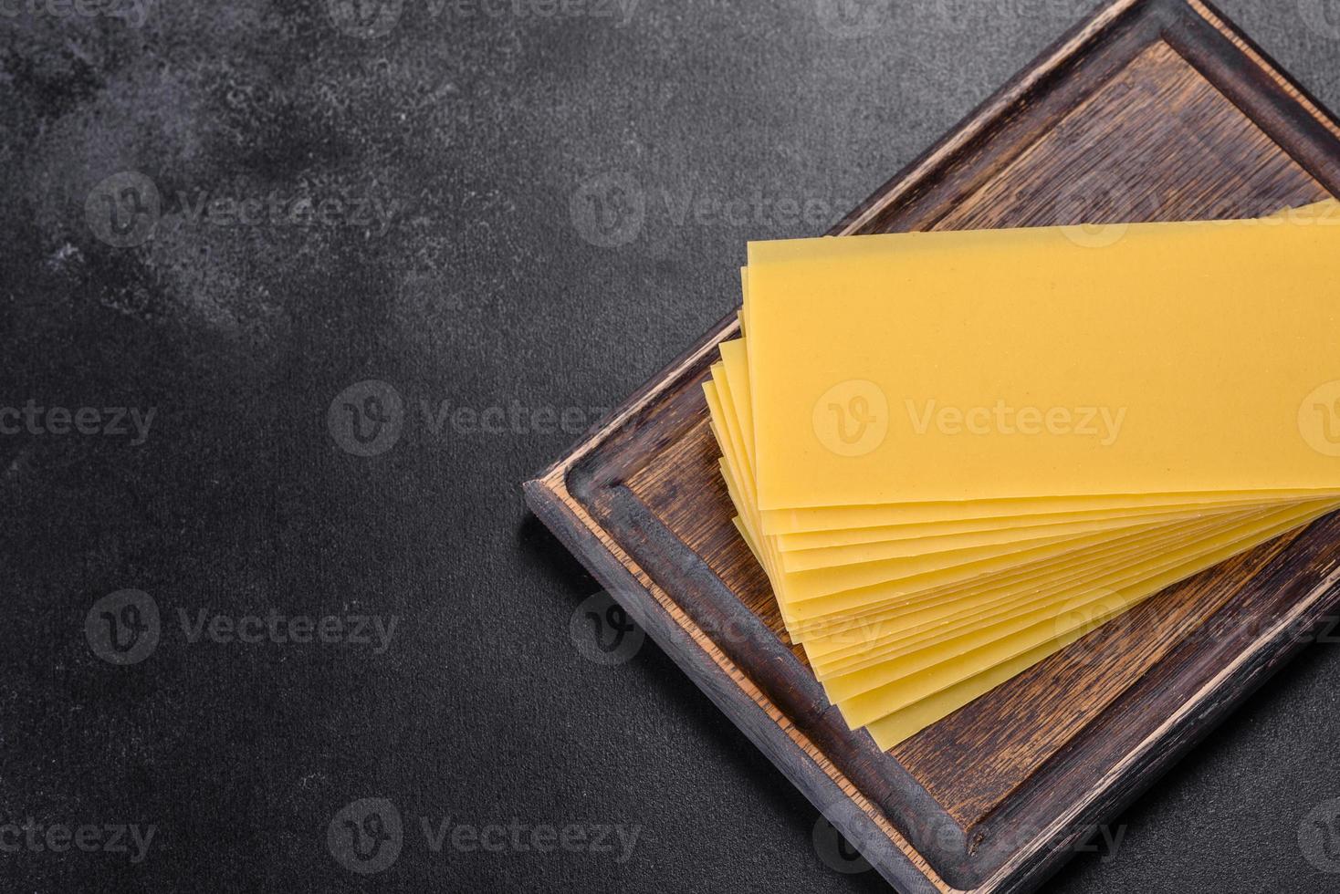 Stack of lasagna sheets on a dark concrete background. Ingredients for lasagna photo