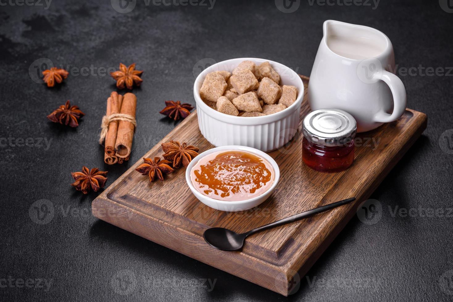 Delicious apricot jam, milk and sugar on a wooden cutting board photo