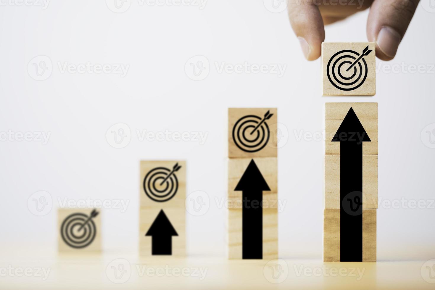 Hand putting target board which printing on wooden cube block on up arrow for enhance and set up business objective target  goal concept. photo