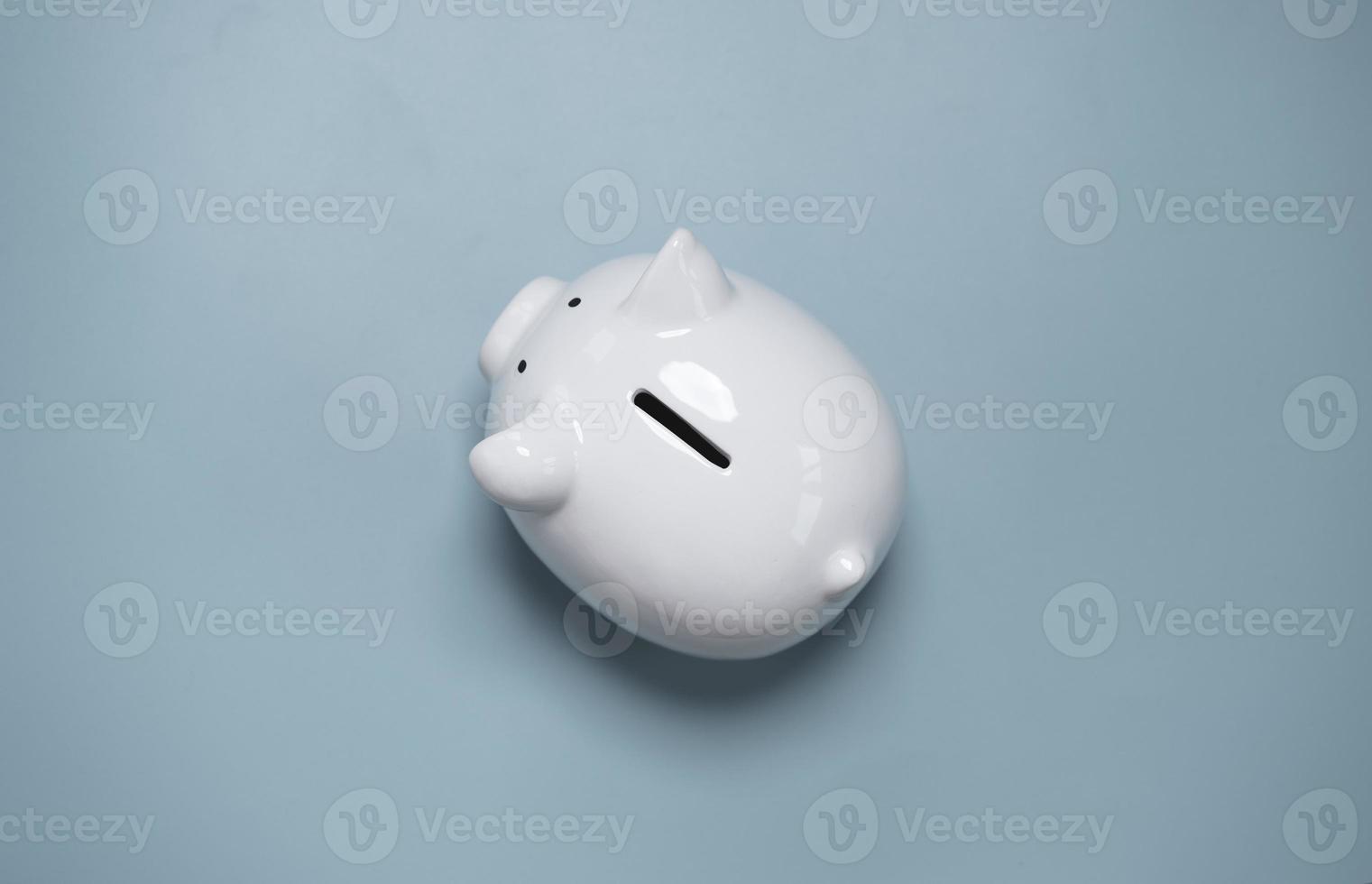 Top view or flat lay of white piggy bank saving on blue background and copy space for deposit and money saving investment concept. photo