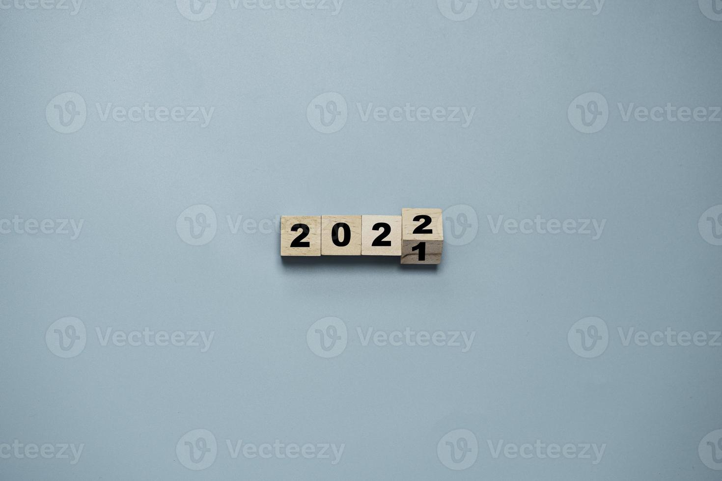 bloque de cubo de madera volteando de 2021 a 2022 sobre fondo azul, preparación para feliz navidad y feliz año nuevo y concepto de representación 3d. foto