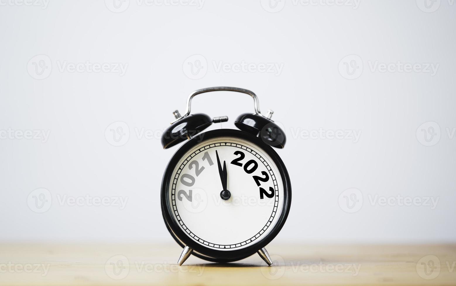 cambio de año de 2021 a 2022 en reloj despertador negro con espacio de copia para feliz navidad feliz año nuevo y comenzar un nuevo concepto de negocio. foto