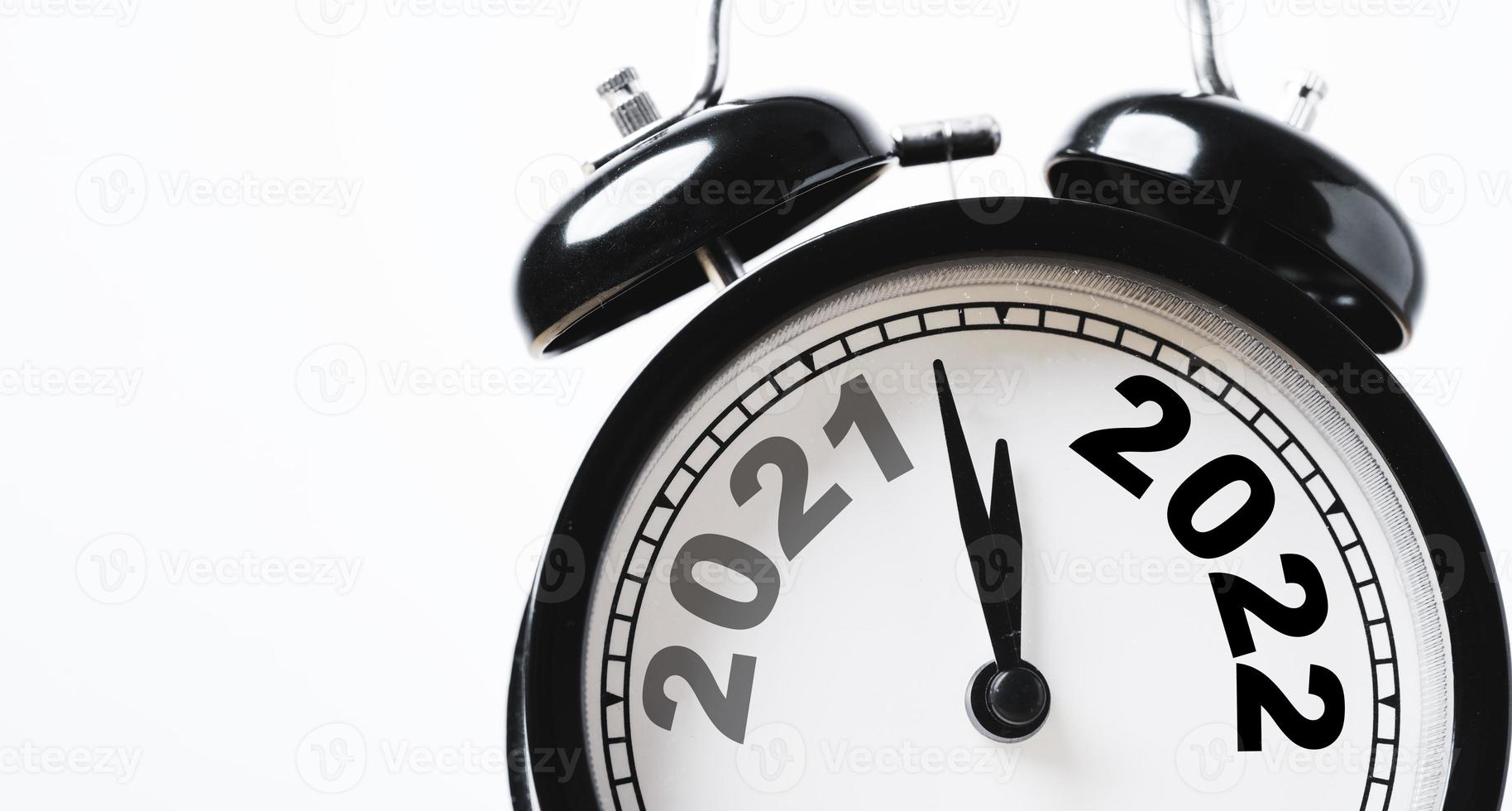 cambio de año de 2021 a 2022 en reloj despertador negro con espacio de copia para feliz navidad feliz año nuevo y comenzar un nuevo concepto de negocio. foto