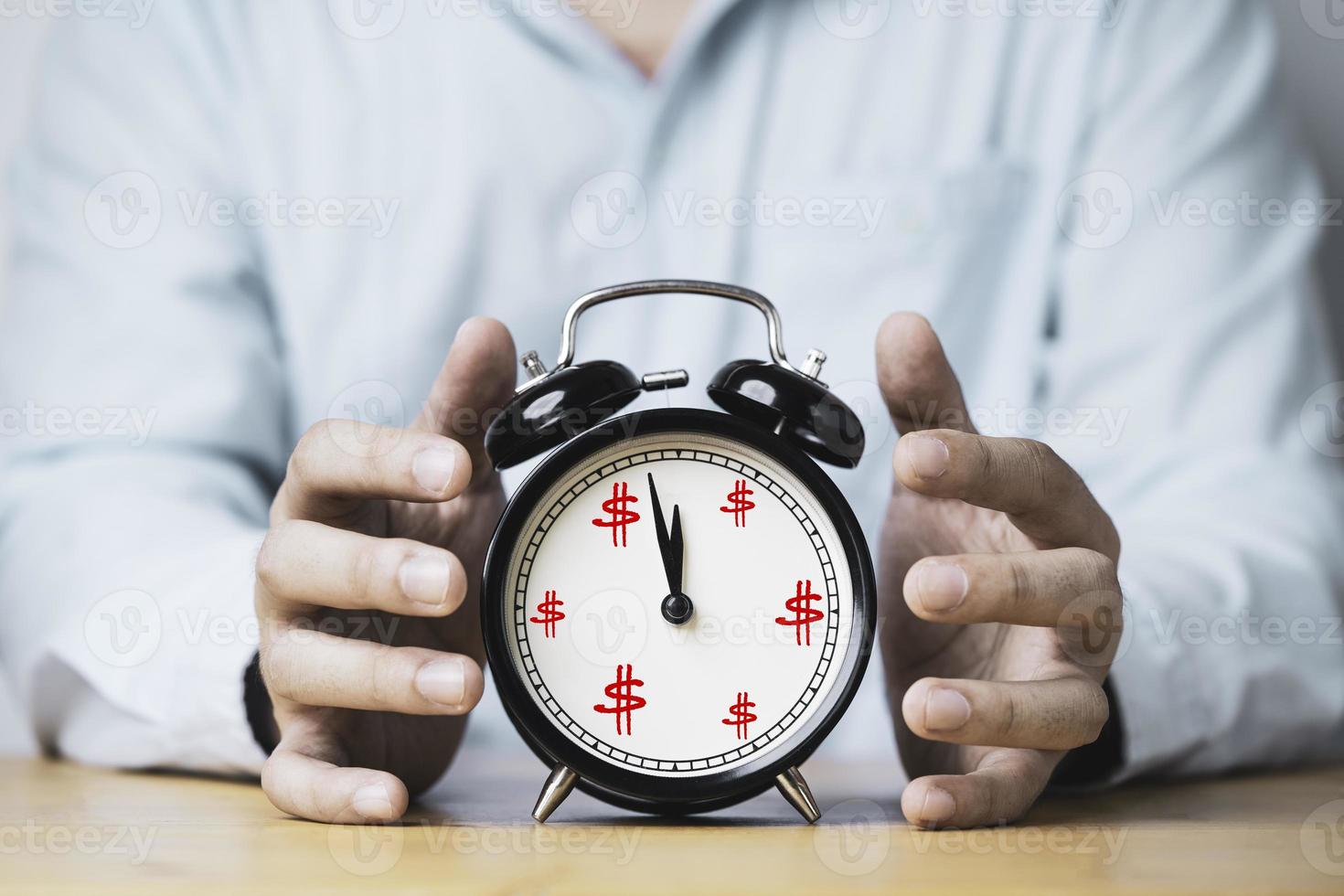 Businessman hand protecting alarm clock with US dollar sign for time and money management concept. photo