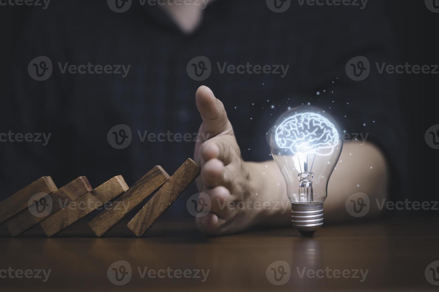 Hand protecting lightbulb with glowing virtual brain from falling wooden block , It is symbol of protect copyright and patent concept. photo