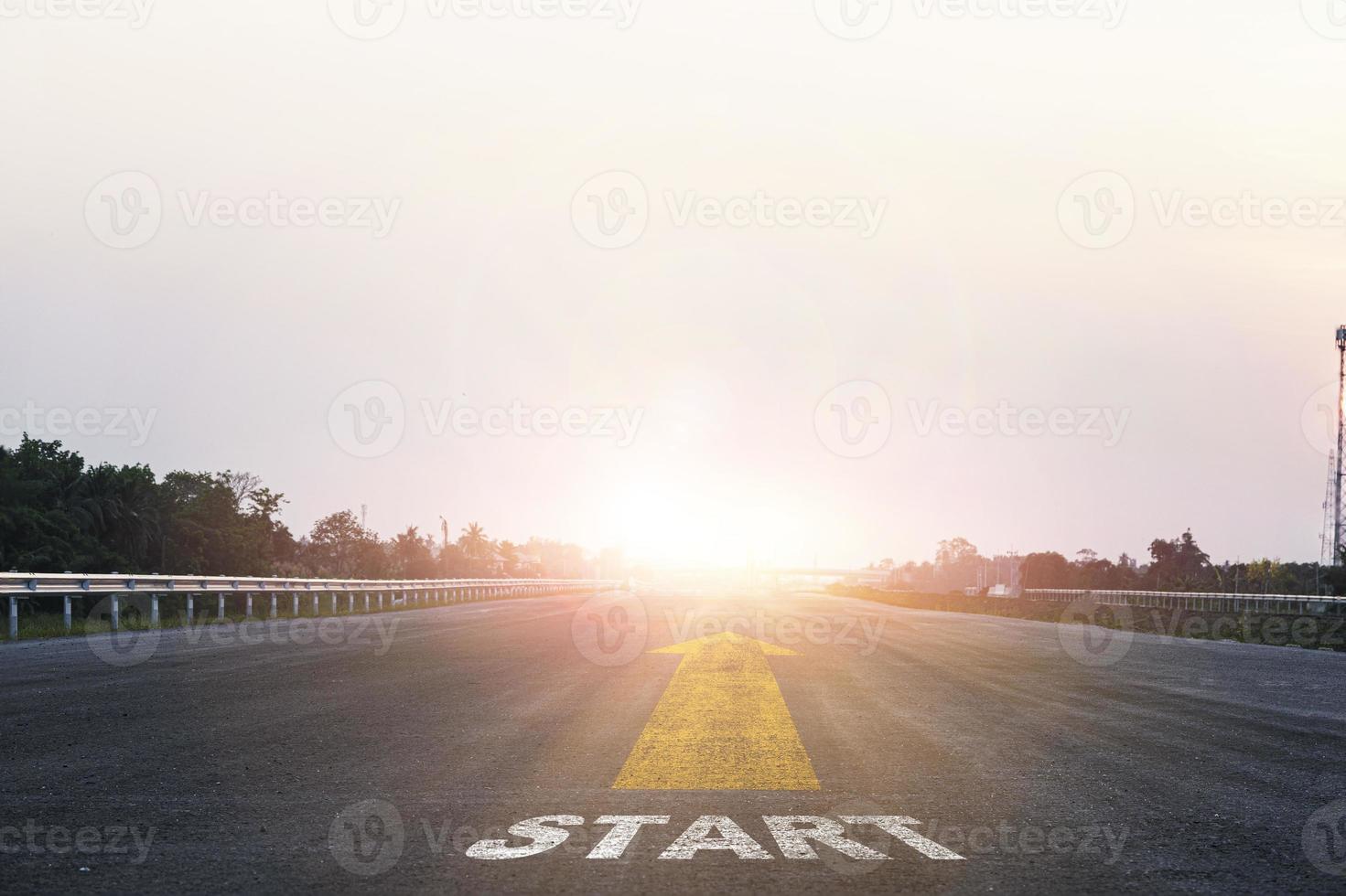 Start line wording with yellow arrow to glowing sunlight on super high way for business and challenge plan of career path concept. photo