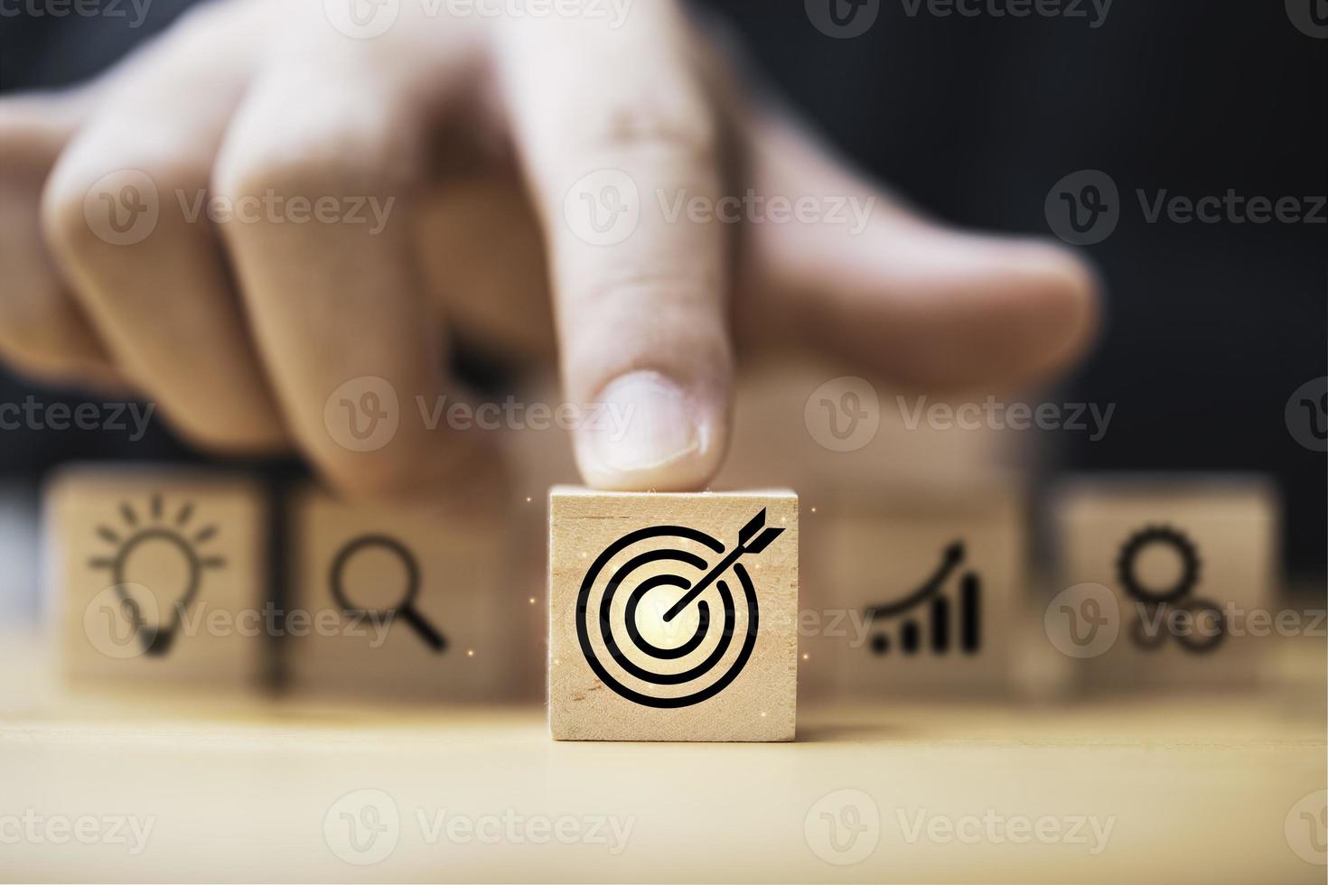 Hand  touching and push target board which printing on wooden cube block on mechanical gear and lightbulb icon  for creative and set up business objective target  goal concept. photo