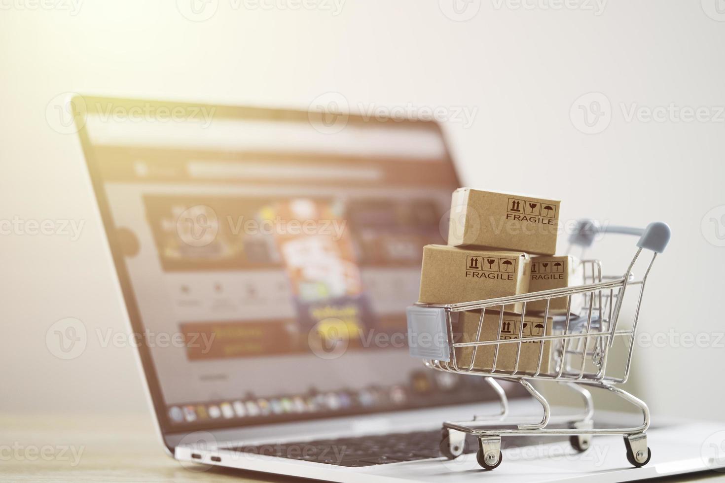 caja de cartón pequeña con carrito de compras en computadora portátil para compras en línea y concepto de comercio electrónico. foto