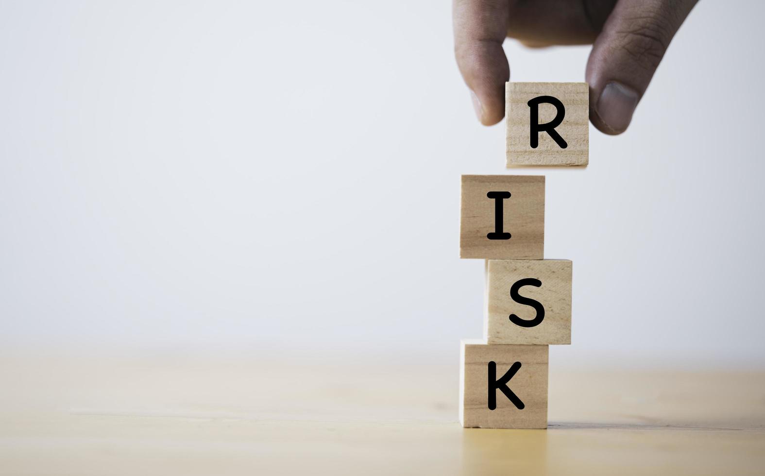 Hand putting and stacking wooden cube block of risk wording for risk management concept. photo