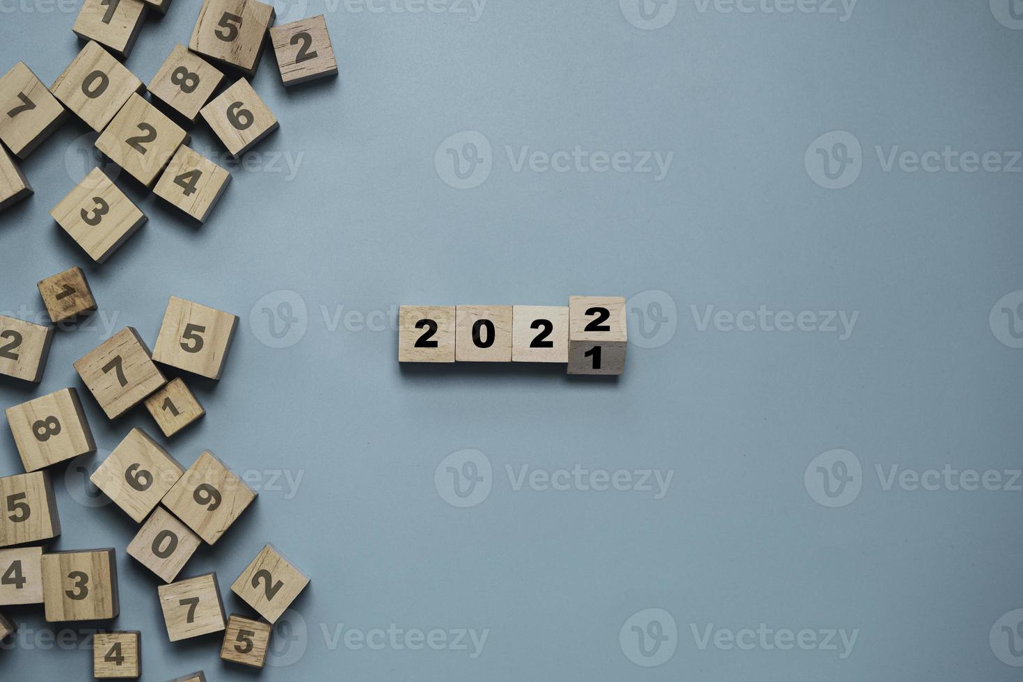 Flipping of wooden cube block for change 2021 to 2022 with other number on blocks on blue background for merry Christmas and happy new year , Start New business and plan concept. photo