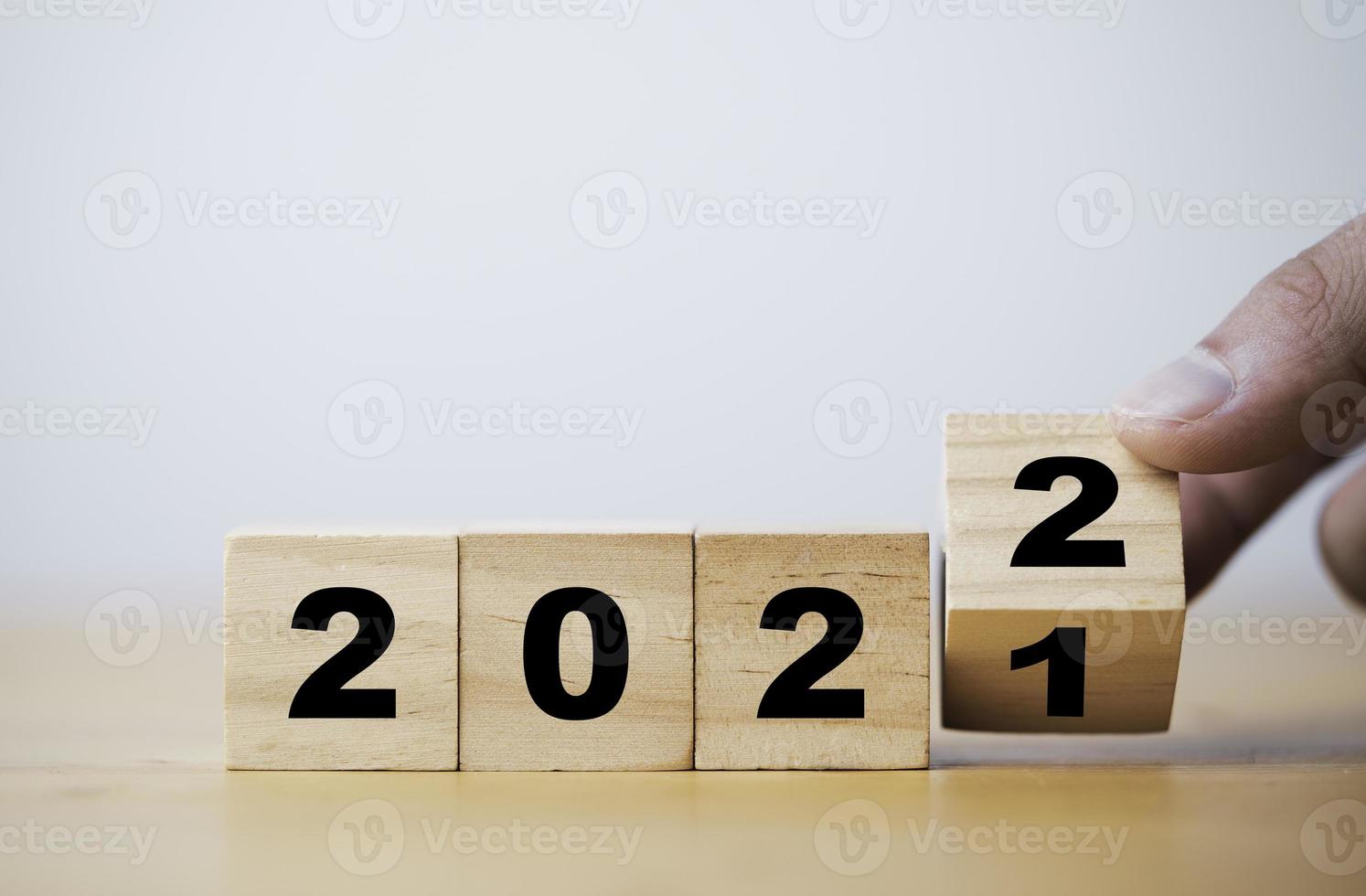 Hand flipping wooden block cube flipping between 2021 to 2022 with bokeh background for change and preparation merry Christmas and happy new year. photo