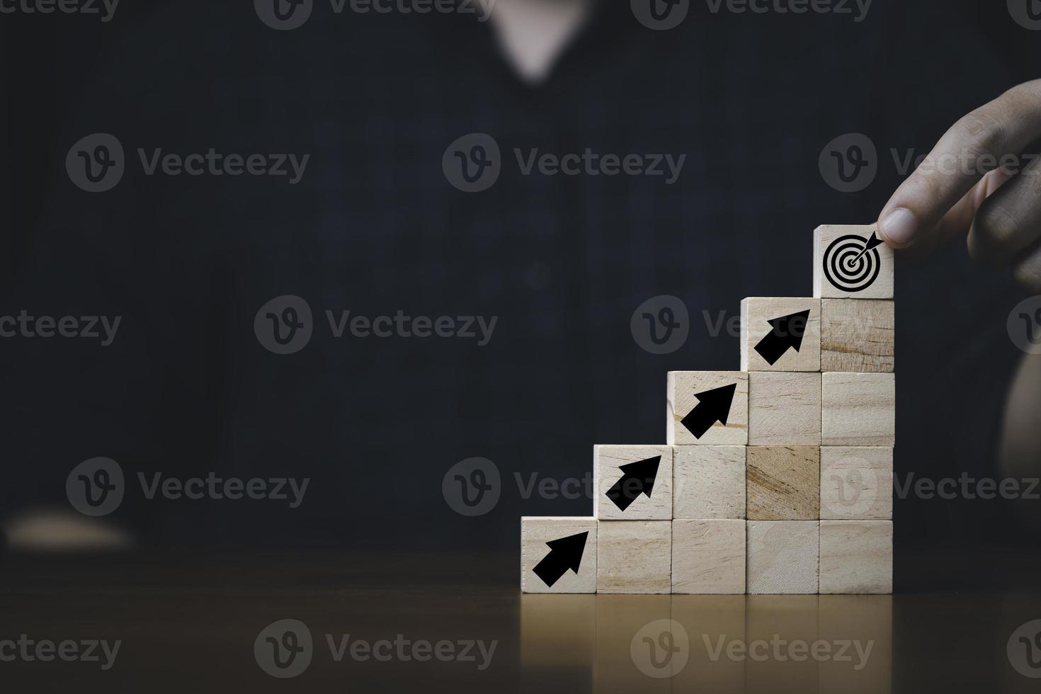 Hand putting and stacking virtual target board and arrow which print screen on wooden cube. Business achievement goal and objective target concept. photo