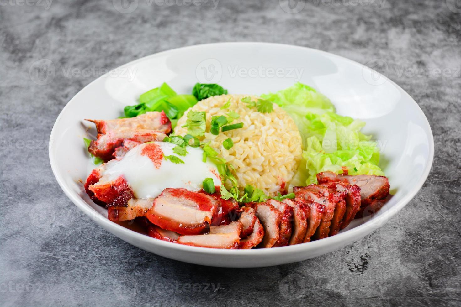 Barbecued red pork and crispy pork in red sauce, served with rice and vegetable on white plate. photo