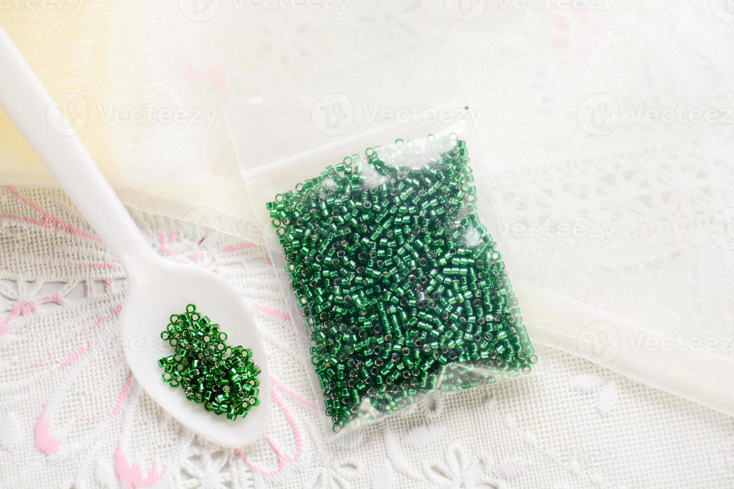Colorful beads on white fabric surface. Various of shapes and colors to make jewelry photo