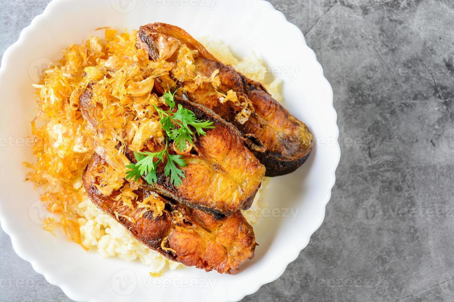 Pescado panga frito en rodajas con ajo, servido con arroz integral. foto