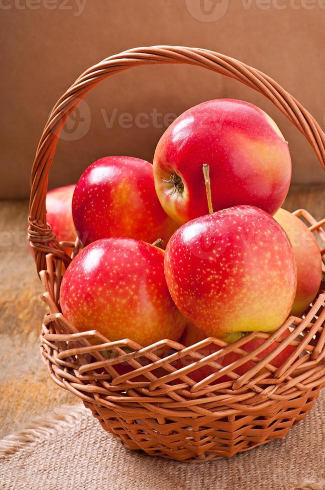 manzanas en una cesta sobre fondo de madera foto