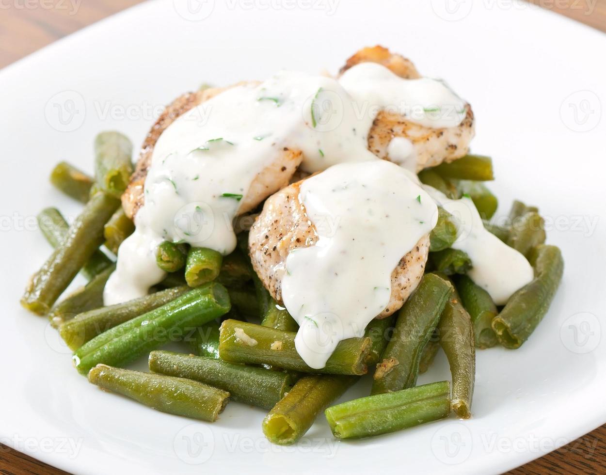 pechuga de pollo a la plancha con judías verdes y salsa en un plato blanco. foto