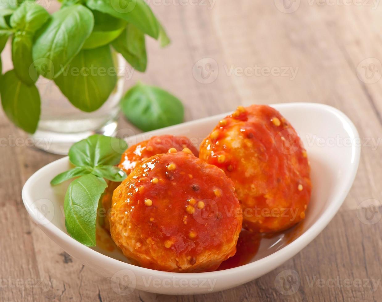 albóndigas en salsa de tomate, decoradas con hojas de albahaca foto