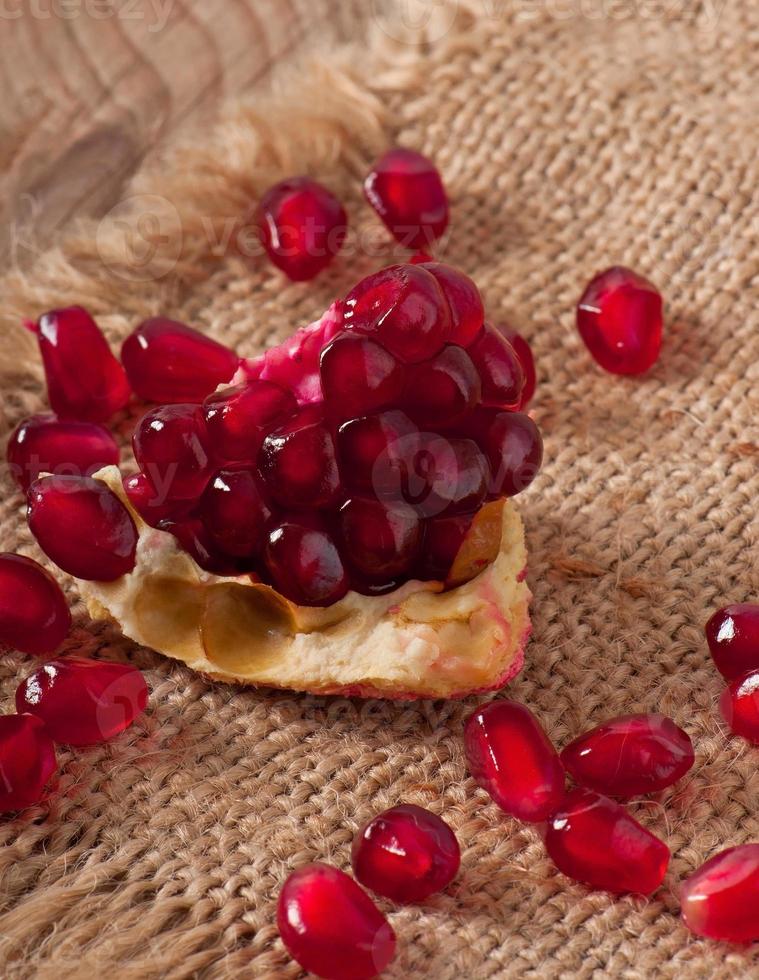 pomegranate seeds on a background of wood and burlap photo