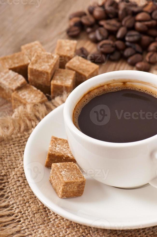 vista de cerca de una taza de café, azúcar moreno y granos de café foto