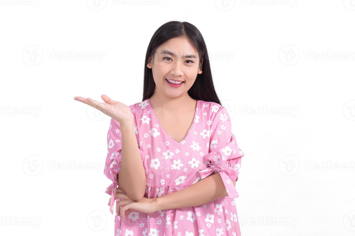 hermosa mujer asiática con vestido rosa muestra la mano para presentar algo sobre fondo blanco. foto