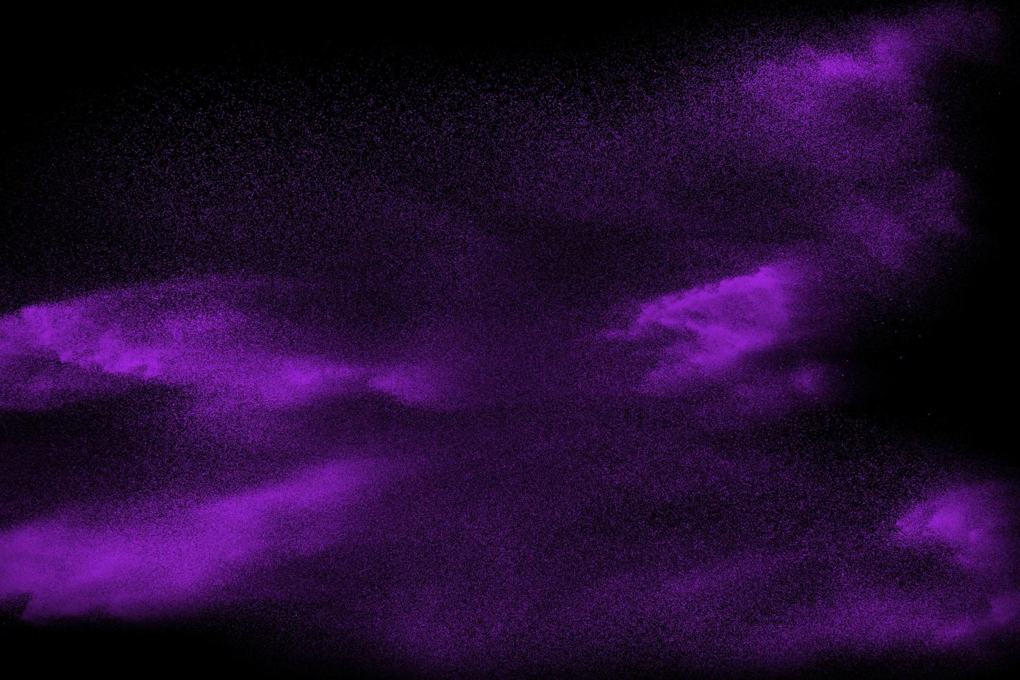 Purple particle dust splash on black background. Purple powder exploding. photo