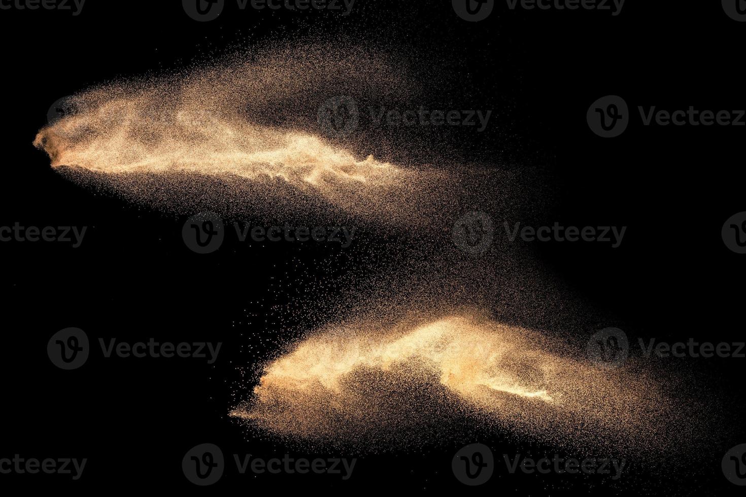 Brown colored sand splash against dark background. Dry river sand explosion isolated on black background. Abstract sand cloud. photo