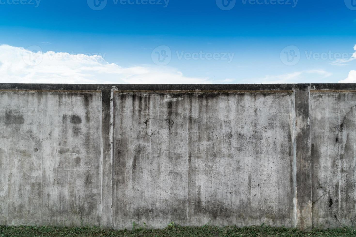 Old cracked gray cement or concrete wall with blue sky as background. Grunge plastered stucco  textured background. photo